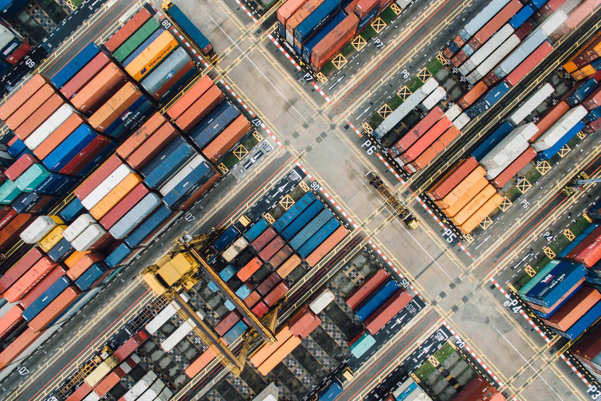 Aerial view of a container yard with rows of stacked shipping containers
